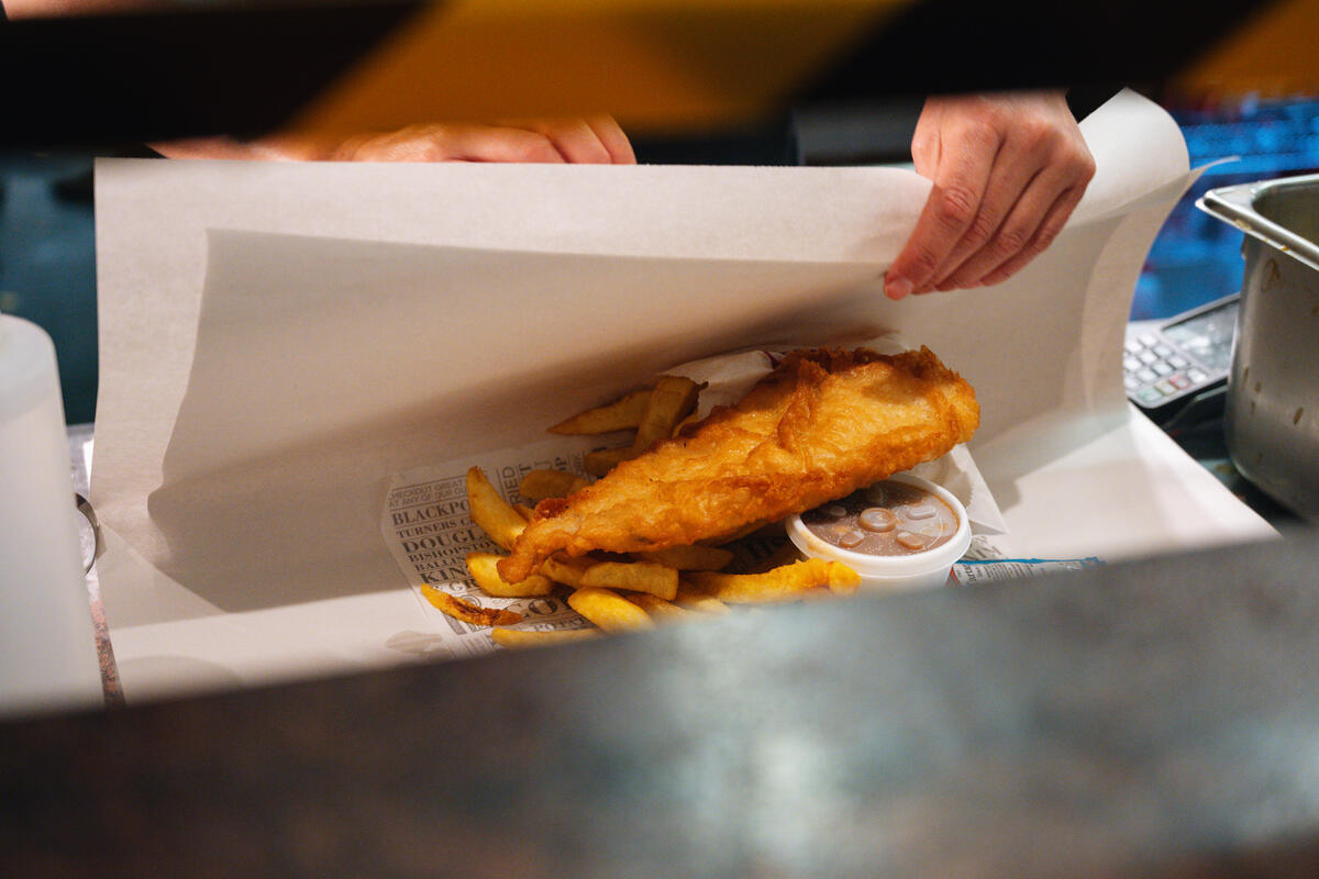 Battered fish and chips being wrapped for takeaway at a Cork chipper